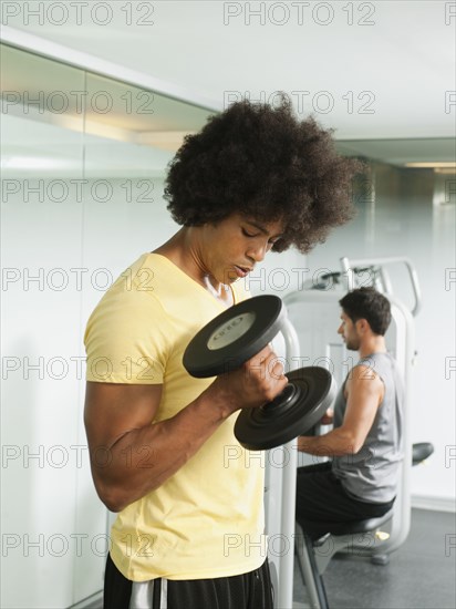 Black man using dumbbells in gym