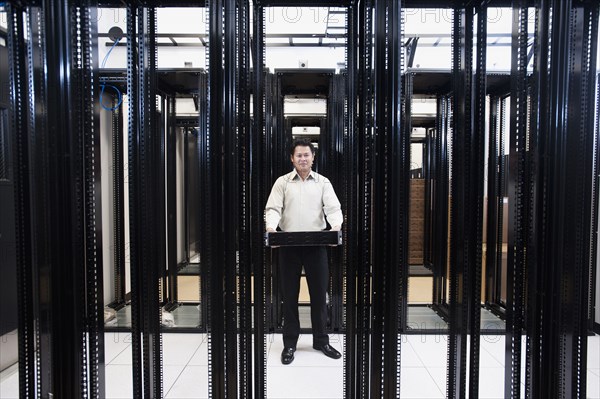 Asian businessman standing in empty server room