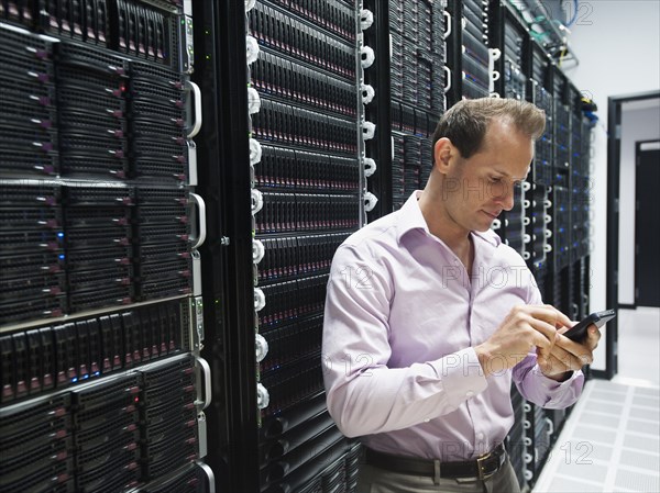 Caucasian businessman using cell phone in server room