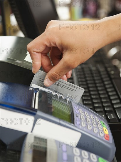 Mixed race woman swiping credit card in store