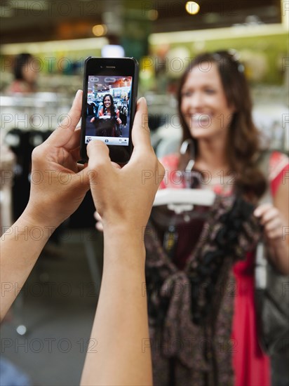 Friends shopping in clothing in store and taking pictures