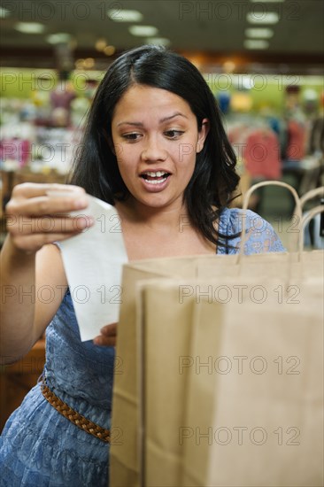 Mixed race woman looking at shopping receipt