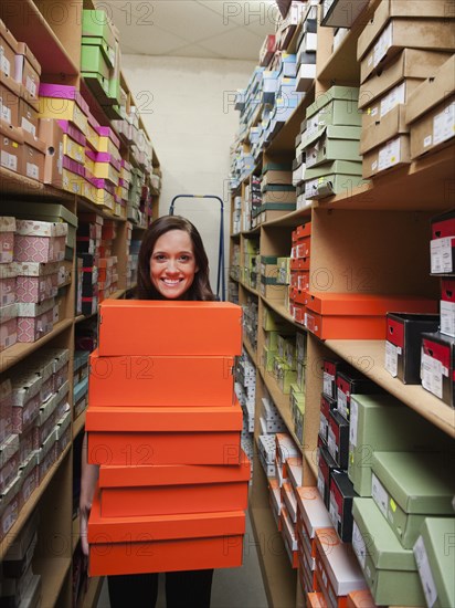 Caucasian woman holding shoes in stockroom