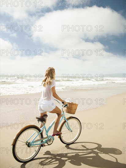 Caucasian woman riding bicycle on beach