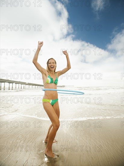 Caucasian woman using plastic hoop on beach