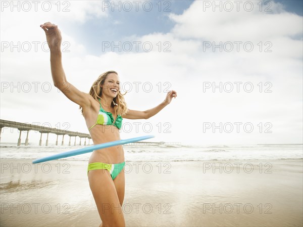 Caucasian woman using plastic hoop on beach