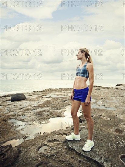 Caucasian woman standing on rocks near beach