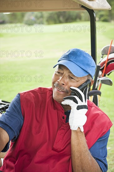 Black man on cell phone in golf cart