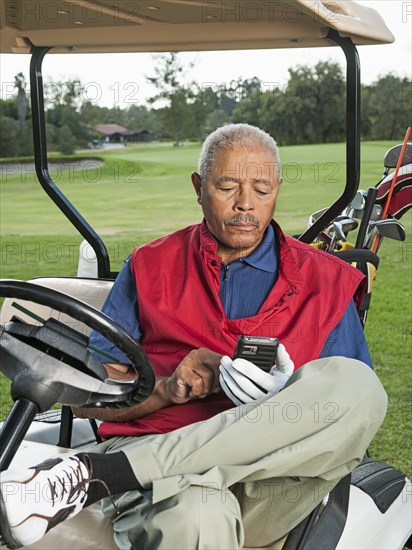 Black man using cell phone in golf cart