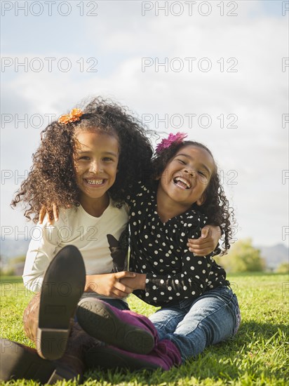 Mixed race girls sitting in grass