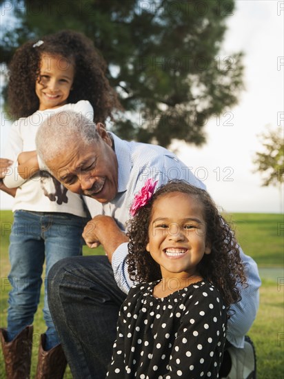 Man playing with granddaughters outdoors