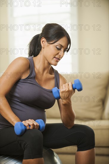 Pregnant Hispanic woman lifting weights