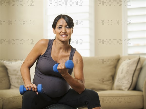 Pregnant Hispanic woman lifting weights