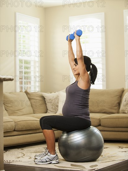 Pregnant Hispanic woman lifting weights