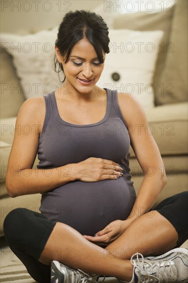 Pregnant Hispanic woman holding her belly