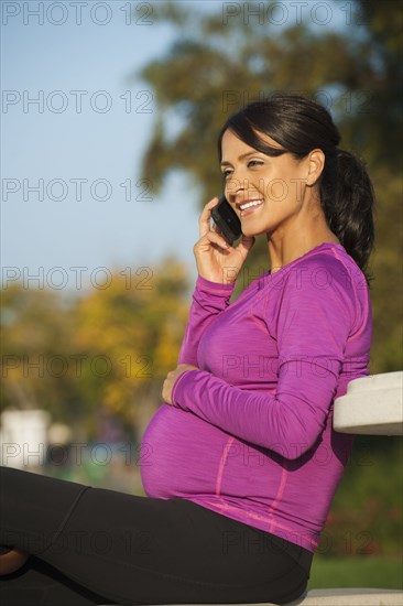 Pregnant Hispanic woman talking on cell phone