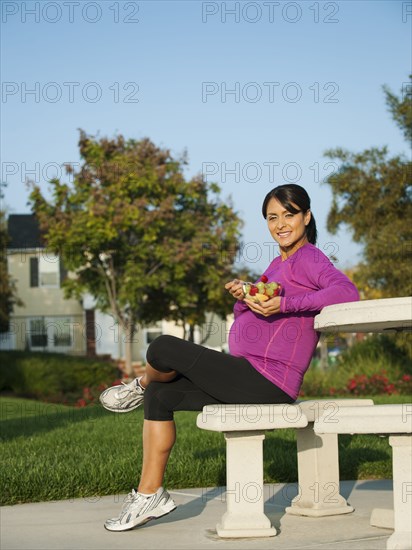 Pregnant Hispanic woman eating fruit salad