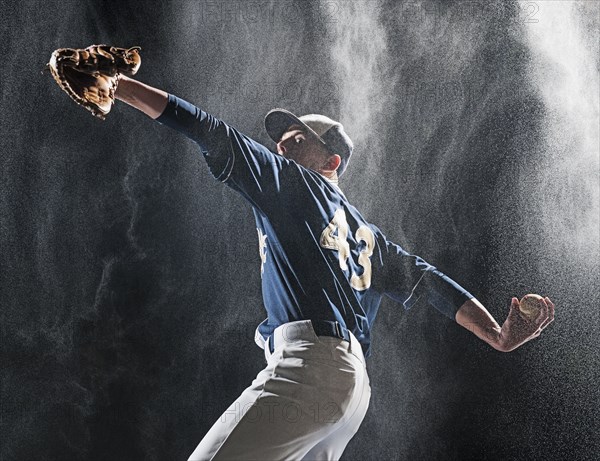 Caucasian baseball player pitching in rain