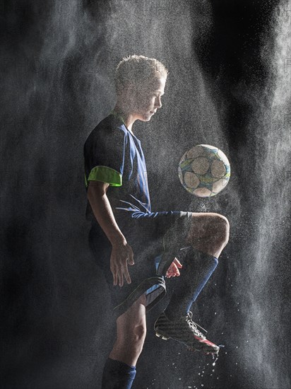 Caucasian soccer player kicking ball in rain