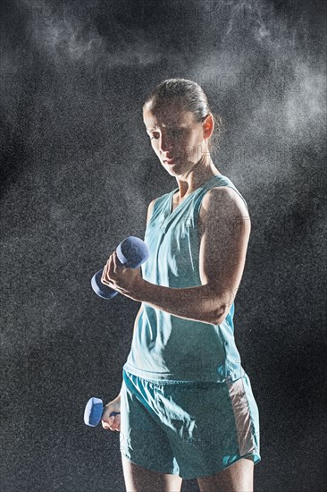 Hispanic woman lifting weights in rain