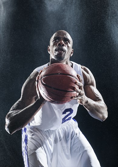 African American basketball player standing in rain