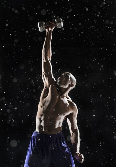 African American athlete lifting weights in rain