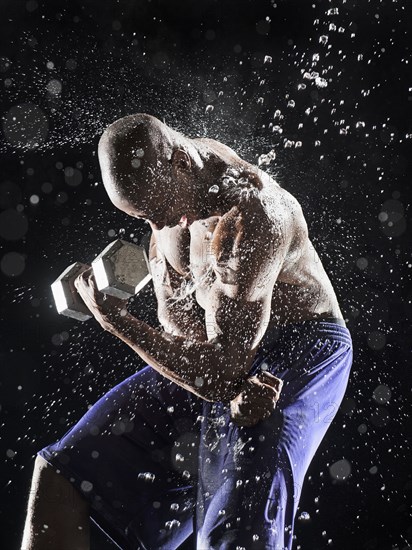 African American athlete lifting weights in rain