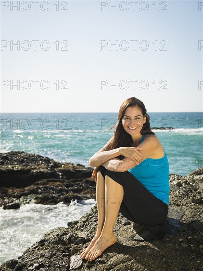 Mixed race woman smiling on rocky beach