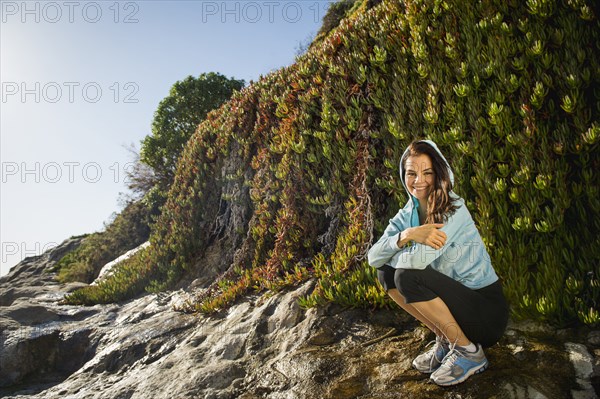 Mixed race woman smiling on rocky beach