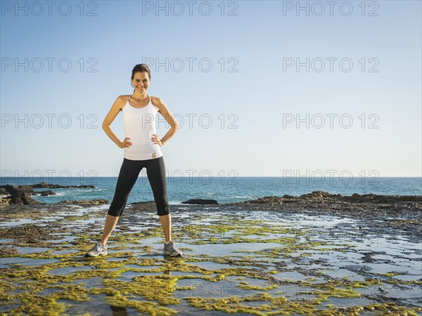 Mixed race runner standing on rocky beach