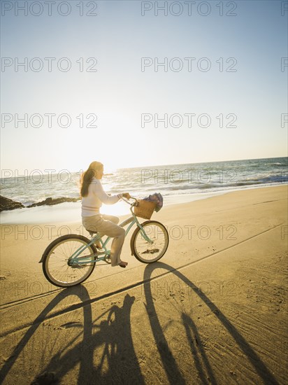 Mixed race woman riding bicycle on beach