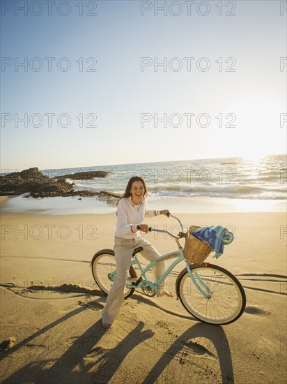 Mixed race woman riding bicycle on beach