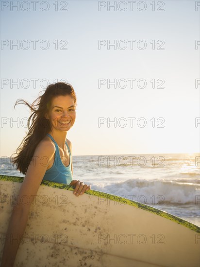 Mixed race woman carrying surfboard on beach