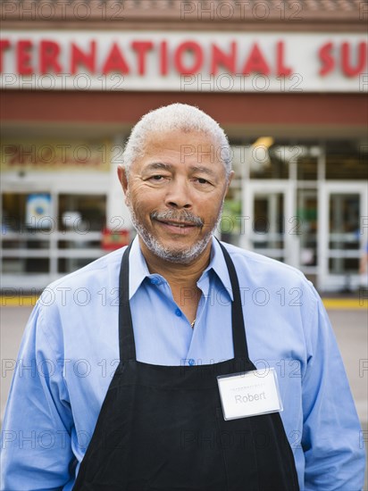 African American worker smiling outside grocery store