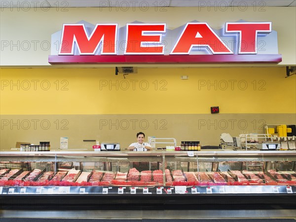 Hispanic butcher at meat counter of grocery store