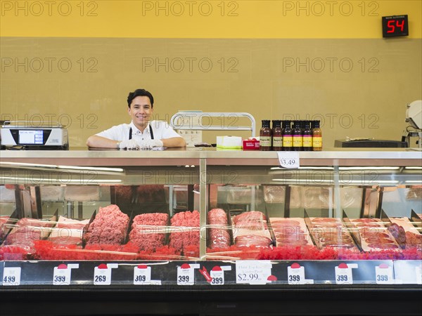 Hispanic butcher at meat counter of grocery store