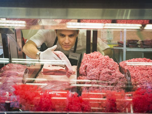 Hispanic butcher at meat counter of grocery store