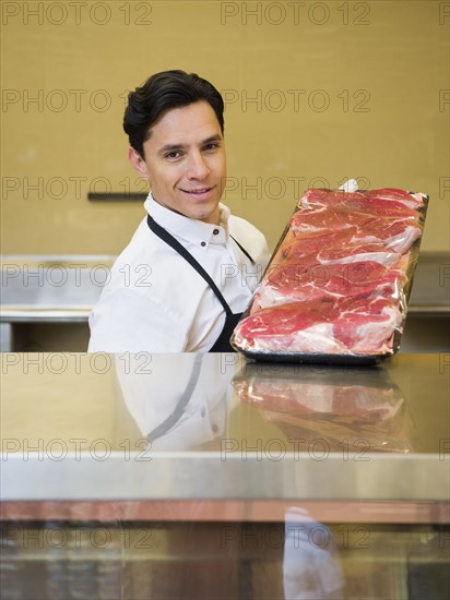 Hispanic butcher at meat counter of grocery store