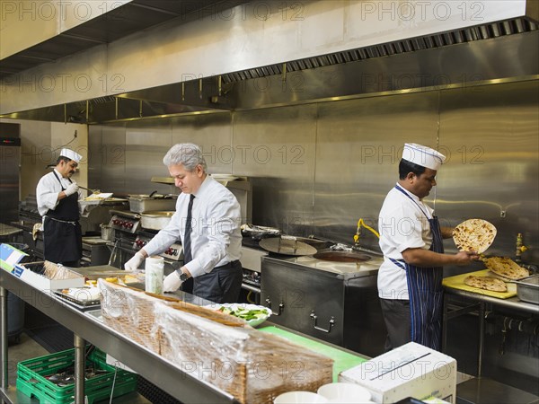 Businessman and chefs working in kitchen