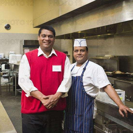 Businessman and chef standing in kitchen