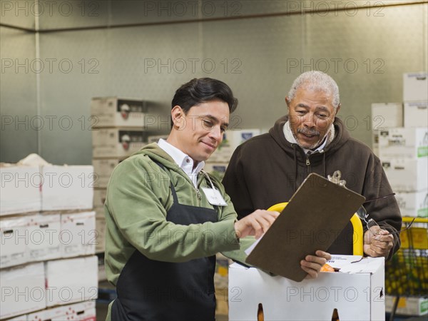 Workers using clipboard in walk-in freezer