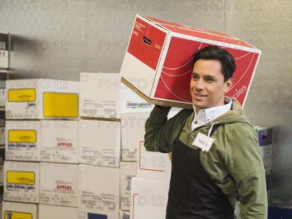 Hispanic worker carrying box in walk-in freezer