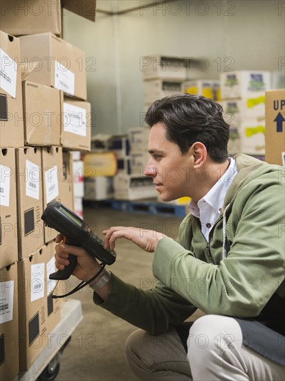 Hispanic worker scanning boxes in walk-in freezer