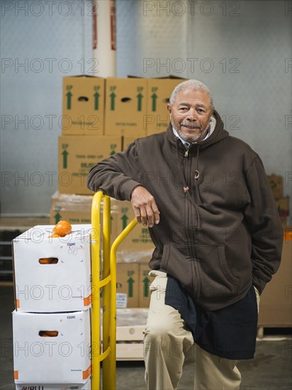 African American worker carting boxes in walk-in freezer