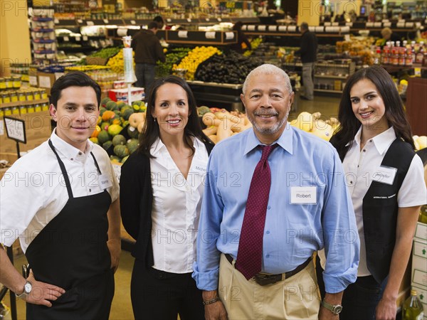 Businessman and workers smiling in grocery store