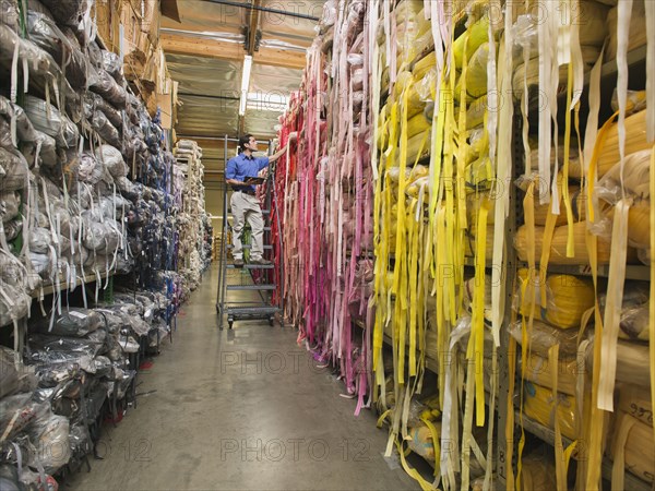 Mixed race worker examining fabric in textile factory