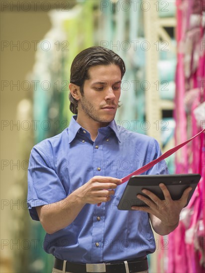 Mixed race worker with tablet computer in textile factory