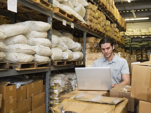 Mixed race worker using laptop in textile factory