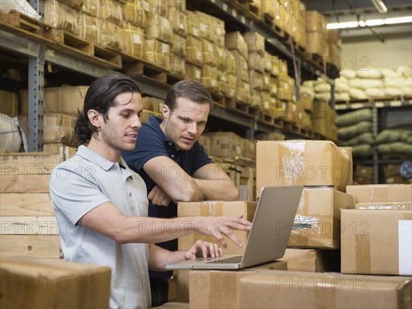 Workers using laptop in textile factory