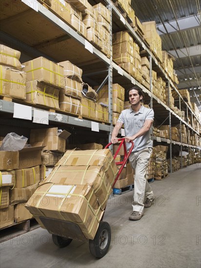 Mixed race worker carting boxes in textile factory